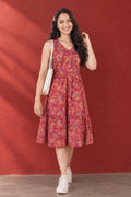 Woman wearing a floral tiered midi dress with sneakers and a shoulder bag.