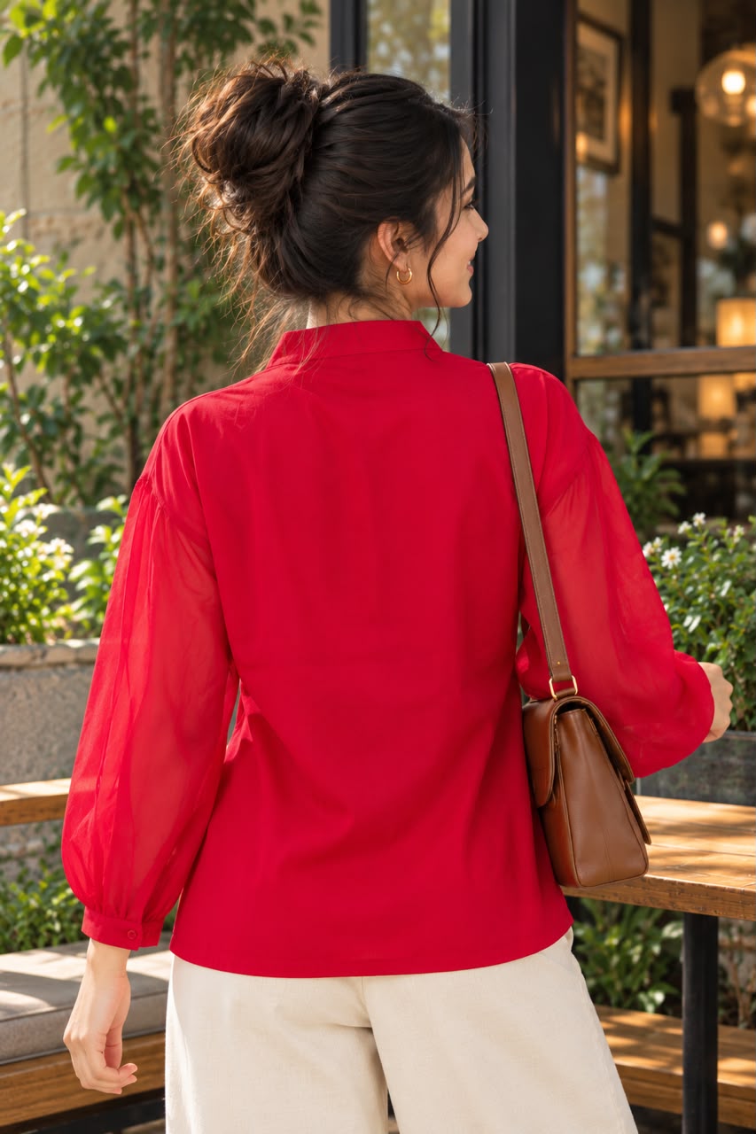 Woman wearing an embroidered women's shirt with sheer puff sleeves and a button-down front
