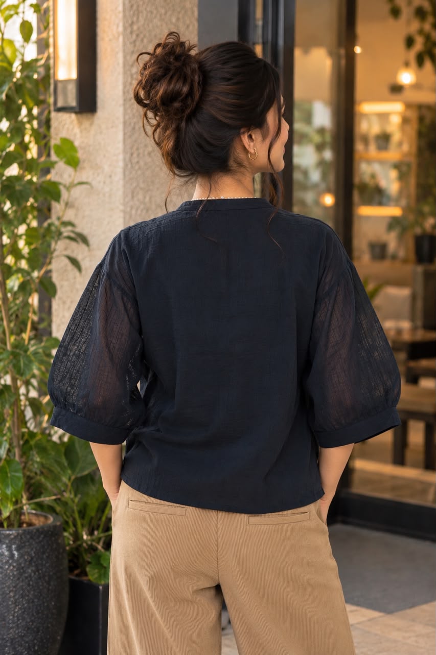 Woman wearing a pearl-trim V-neck top with puff sleeves.